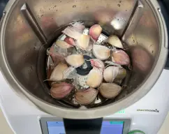 Step <p>Añadir los ajos (podemos quitar la parte del tallo ahora o una vez pelados), cubrir con agua y usar la FUNCIÓN Pelador. 1 min.</p> illustration